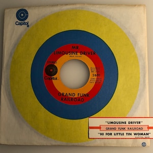 May include: A vintage vinyl record with a yellow, blue and red concentric circle design. The record is titled "Mr. Limousine Driver" by Grand Funk Railroad. The label is from Capitol Records and the record number is 2691.