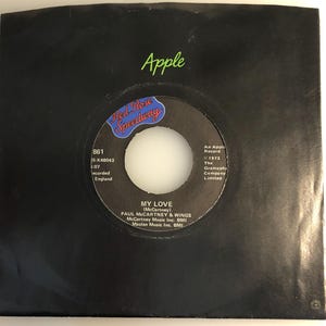 May include: A black record sleeve with the Apple logo in green at the top. The record label features the text "MY LOVE" by Paul McCartney & Wings, with the Red Rose Speedway logo.
