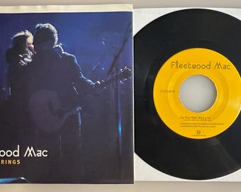 May include: A Fleetwood Mac vinyl record and its sleeve. The sleeve features a dark blue concert photograph with the text Fleetwood Mac and Silver Springs. The black vinyl record has a yellow center label with the text Fleetwood Mac and Go Your Own Way.