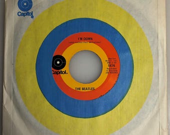 May include: A yellow, blue, and orange vinyl record with the text "I'M DOWN" by "The Beatles" and the Capitol Records logo. The record number is 5476.