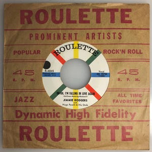 May include: A vintage 45 RPM record label for the song "Oh-Oh, I'm Falling in Love Again" by Jimmie Rodgers, featuring a red, white and green Roulette Records label with the text "Dynamic High Fidelity" printed below.