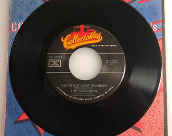 May include: Black vinyl 45 RPM record with a white label. The label has the title "You've Got Your Troubles" by "The Fortunes" and the text "Collectables "Back to Back Hit Series"  "Send for Free Catalog"  "MILLS MUSIC INC. (ASCAP) 3:20"  "COLLECTABLE RECORD CORP. BOX 35, NARBERTH PA 19072"  "Courtesy of Dominion Entertainment Incorporated"