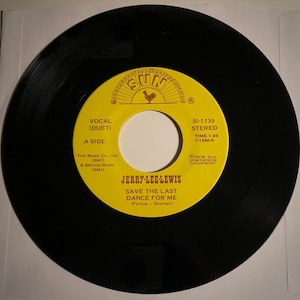 Puede incluir: Un disco de vinilo negro con una etiqueta amarilla. La etiqueta presenta el texto "JERRY-LEE-LEWIS SAVE THE LAST DANCE FOR ME" y el logotipo de Sun Records. El disco está en una funda blanca. Grabación estéreo.