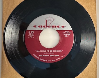 May include: A black vinyl record with a red and white label featuring the text "ALL I HAVE TO DO IS DREAM" by The Everly Brothers. The record is 7 inches in diameter and is in a brown paper sleeve.