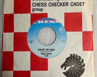 May include: A vintage 45 RPM record by Chuck Berry, titled "BACK IN USA," with a blue and white label. The record is housed in a sleeve with a red and white checkerboard pattern and the text "Distributed by the CHESS CHECKER CADET group."