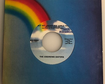 May include: A vintage 45 RPM record by The Andrews Sisters. The record is titled "Don't Sit Under The Apple Tree (With Anyone Else But Me)" and features a rainbow design on the cover. The label is MCA Records.