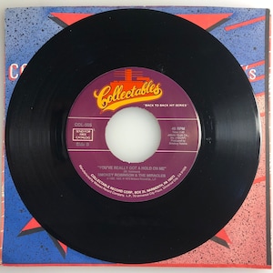 May include: A black vinyl record with a purple and gold label featuring the text "Collectables" and "You've Really Got a Hold on Me" by Smokey Robinson & The Miracles. The record is on a colorful sleeve.