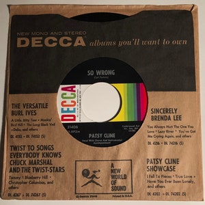 May include: A vintage 45 RPM vinyl record in its original brown paper sleeve. The record features Patsy Cline's song "So Wrong" and other artists. The sleeve has the Decca Records logo and song titles. The record is a piece of music history.