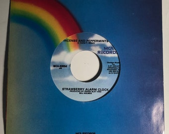 May include: A white vinyl record with a rainbow background. The record is labeled "MCA Records" and features the song "Strawberry Alarm Clock" by the band "Strawberry Alarm Clock". The record also includes the song "Incense and Peppermints" by the band "The Strawberry Alarm Clock".