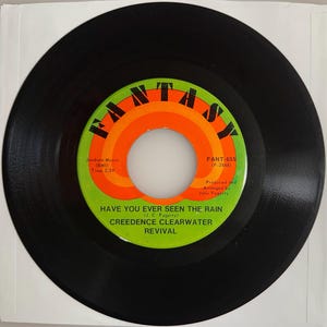 May include: A black vinyl record with a green, orange, and white label. The label features the word "FANTASY" in a rainbow design and the song title "HAVE YOU EVER SEEN THE RAIN" by Creedence Clearwater Revival.