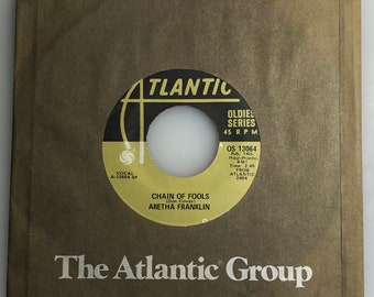 May include: A black and white 45 RPM vinyl record with a brown paper sleeve. The record is titled "Chain of Fools" by Aretha Franklin. The record is part of the "Oldies Series" and is from Atlantic Records.