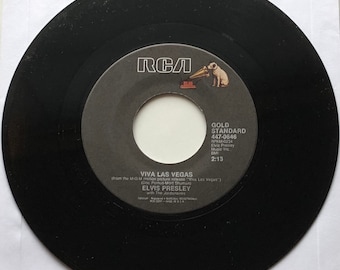 May include: A black vinyl record with a label that says "RCA" and "Viva Las Vegas" by Elvis Presley. The record is from the M-G-M motion picture release "Viva Las Vegas". The label also includes the song title, "Viva Las Vegas", the songwriters' names, "Doc Pomus-Mort Shuman", the record label, "RCA", the record number, "447-0646", and the song's length, "2:13".