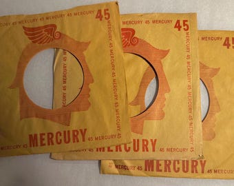 May include: Three vintage Mercury 45 RPM record sleeves. The sleeves are tan with orange graphics, including a profile of a person and the word "MERCURY". The number "45" is printed in the upper right corner.