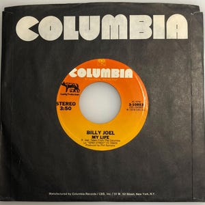 Può includere: Un disco in vinile nero e arancione con il titolo "Billy Joel - My Life" e l'etichetta Columbia Records. Il disco è un disco da 45 giri e fu pubblicato nel 1978.