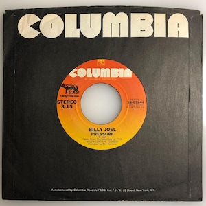 Può includere: Un disco in vinile nero e arancione con il titolo "Pressure" di Billy Joel. Il disco è tratto dall'album "The Nylon Curtain" ed è stato prodotto da Phil Ramone. L'etichetta del disco è Columbia Records.