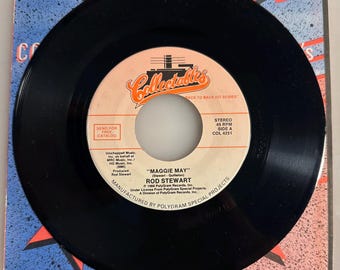 May include: A black vinyl record with a white and orange label featuring the text "MAGGIE MAY" by Rod Stewart. The record is a 45 RPM single from the "Collectables" series, with a blue and red patterned sleeve.