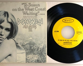 May include: A 45 RPM vinyl record by Donovan, titled "To Susan on the West Coast Waiting". The record is yellow with black text and is on a black vinyl record. The record is on a white background.