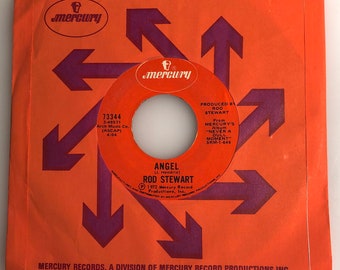 May include: A red and purple 45 RPM record sleeve with the title "Angel" by Rod Stewart. The sleeve features a Mercury Records logo and the text "Produced by Rod Stewart" and "From Mercury's Album "Never a Dull Moment" SRM-1-646".