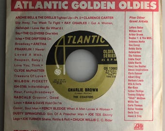 May include: A vintage record label for the song "Charlie Brown" by The Coasters. The label is white with black text and a red and black Atlantic Records logo. The song is from the "Oldie Series" and is a 45 RPM record. The label lists other artists on the Atlantic label, including Aretha Franklin, Ray Charles, and Wilson Pickett.