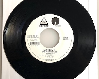 May include: A black vinyl record with a white label featuring the text "MAROON 5 She Will Be Loved". The record is in a white paper sleeve. The label includes the "octone" and "j records" logos.