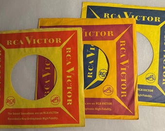 May include: Three vintage RCA Victor record sleeves. The sleeves are yellow, red, and blue with the RCA Victor logo and text. The sleeves have a circular cutout in the center for the record label.