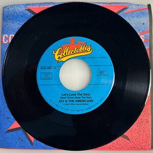 May include: A black vinyl record with a blue and white label featuring the text "Collectables" and the song title "Let's Lock The Door (And Throw Away The Key)" by Jay & The Americans. The record is in a colorful sleeve.