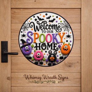 May include: A circular sign featuring the text Welcome to our SPOOKY HOME in black, purple, and orange lettering. The design includes four colorful monsters, black bats, and spider webs against a white background with orange and black polka dots.