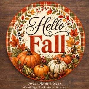 May include: A round aluminum sign featuring the text Hello Fall in black and red script and block lettering. The design includes a border of autumn leaves, acorns, and berries surrounding a collection of orange and white pumpkins on a plaid background.