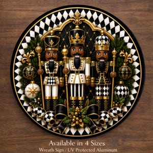 May include: A round aluminum wreath sign featuring three nutcrackers in black, white, and gold uniforms. The design includes a diamond-patterned border, gold scepters, ornaments, and greenery. Text reads: Available in 4 Sizes, Wreath Sign / UV Protected Aluminum.