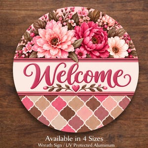 May include: A round aluminum sign featuring a floral arrangement of pink and white flowers at the top, the word Welcome in dark pink script across a cream horizontal band, and a pink and brown quatrefoil pattern on the bottom half.