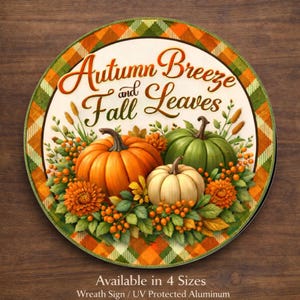 May include: A round aluminum sign featuring the text Autumn breeze and Fall leaves in brown script. The design includes a large orange pumpkin, a green pumpkin, and a small white pumpkin surrounded by orange flowers and green foliage.