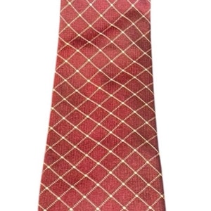 May include: A red tie with a white grid pattern. The tie has a diamond pattern with white dots at each intersection. A small emblem is visible near the bottom. This tie is suitable for formal occasions.