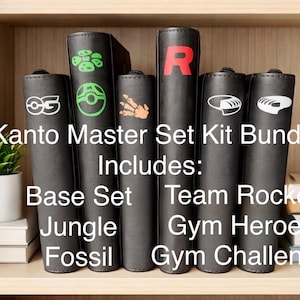 May include: A collection of black binders with various colorful graphics and text, including the text "Kanto Master Set Kit Bundle Includes: Base Set, Jungle, Fossil, Team Rocket, Gym Heroes, Gym Challenge."