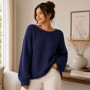 May include: A navy blue long-sleeved sweater with a ribbed knit texture, a wide boat neckline, and dropped shoulders. The sweater features a loose, relaxed fit with cuffed sleeves and a straight hemline, crafted from a thick, solid-colored yarn.