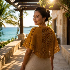 May include: A mustard yellow knitted capelet featuring an intricate openwork lace pattern throughout the fabric. The garment has a round neckline and short, flared sleeves that drape over the shoulders, providing a lightweight layer over a dress.