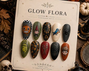 May include: A set of ten press-on nails on a display card labeled GLOW FLORA. The nails feature detailed illustrations including a jack-o'-lantern, a gnome, autumn leaves, a blue bird with a key, a spider web, a frog, scissors, and a teapot character.