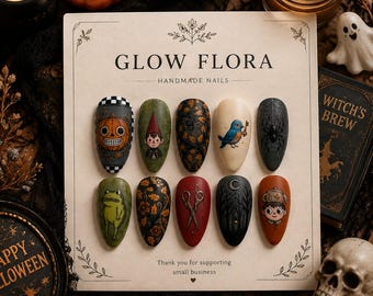 May include: A set of ten press-on nails on a display card labeled GLOW FLORA HANDMADE NAILS. The nails feature detailed illustrations including a jack-o'-lantern, a gnome, autumn leaves, a blue bird, a spider, a frog, scissors, and a forest scene.