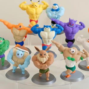 Può includere: Una collezione di dieci figurine colorate di vari personaggi, ognuno con un fisico muscoloso. Le figurine sono esposte su un supporto trasparente a più livelli. I personaggi sono in vari colori, tra cui giallo, arancione, blu, verde, viola e bianco.