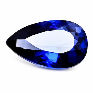 May include: A pear-shaped loose gemstone with a deep, saturated royal blue color. The stone features a faceted surface with a prominent central reflection, creating a clear contrast between the dark blue edges and the bright, white light center.