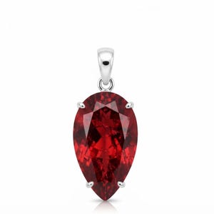 May include: A pear-shaped, deep red gemstone pendant set in a polished silver-toned metal prong setting. The faceted stone features a brilliant cut that reflects light, suspended from a simple, smooth silver-toned metal bail at the top.