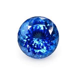 May include: A round, faceted gemstone with a vibrant, deep blue color. The stone features a complex, symmetrical pattern of triangular and diamond-shaped facets that reflect light, creating a brilliant, sparkling appearance across its surface.