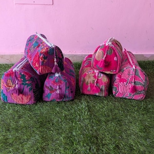 Peut inclure: Un ensemble de six trousses cylindriques en velours côtelé magenta. Chaque trousse présente un imprimé floral et aviaire vibrant dans des tons de vert, orange et rose, avec une fermeture éclair blanche et un petit pompon assorti.