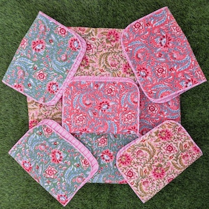 Può includere: Un set di tessuti a motivi floreali nei toni del rosa, verde e beige. Il set comprende un grande pezzo centrale e diversi pezzi quadrati più piccoli con bordi rosa. Il design floreale presenta fiori e foglie stilizzati.