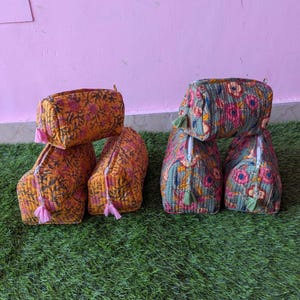 Puede incluir: Cinco neceseres acolchados con cremalleras y pequeñas borlas. Tres neceseres tienen una base naranja con un estampado floral, mientras que dos tienen una base gris verdosa con un estampado floral. Cada neceser tiene una forma rectangular estructurada.