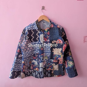 May include: A long-sleeve jacket featuring a patchwork design with various blue, white, and multi-colored floral and geometric patterns. The jacket has a button-front closure, a mandarin collar, and visible stitching throughout. The text ShivtextileShop is visible.