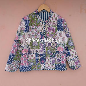 May include: A quilted jacket featuring a patchwork design with floral and botanical patterns in shades of pink, green, and blue on a white background. The jacket has a round neckline, long sleeves, two front pockets, and the text ShivtextileShop.