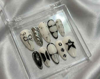 Unhas postiças artesanais inspiradas no BTS: estilo gótico preto e branco com detalhes cromados prateados.
