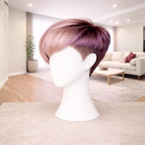 May include: A short wig with a layered style, presented on a white mannequin head. The wig showcases a mix of colours, including light pink, rose, and deep purple. The hair is styled with a side parting and a close-cropped undercut.