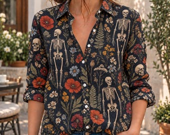 May include: A long-sleeved button-down shirt featuring a dark background with a repeating pattern of human skeletons, red poppies, yellow wildflowers, and green ferns. The shirt has a classic collar, a front button placket, and cuffed sleeves.