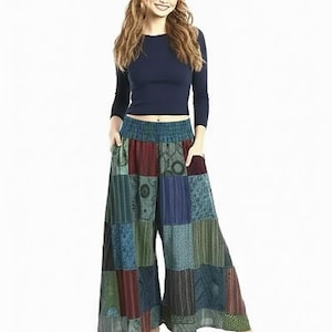 May include: A woman wearing a navy blue long-sleeve top, a patchwork patterned wide-leg pants, and a matching headband. The pants feature a variety of colors and patterns, including red, green, blue, and teal. The outfit is casual and bohemian.